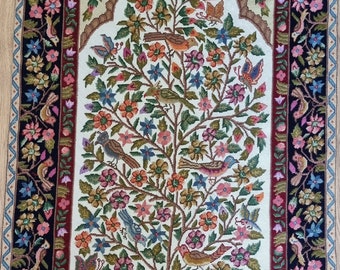 May include: A white rug with a detailed floral design and birds. The rug has a black, red, and blue border with a fringe.