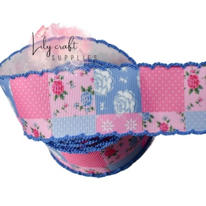 May include: A roll of decorative ribbon with a patchwork design. The ribbon features alternating squares of pink with white polka dots and floral patterns, and light blue squares. The edges are trimmed with blue crochet.