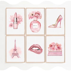 Può includere: Un set di sei stampe artistiche da parete incorniciate con illustrazioni a tema rosa: un rossetto con fiori, un flacone di profumo con fiori etichettato Belle, una scarpa col tacco, la Torre Eiffel, labbra glitterate e libri con fiori.