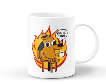 May include: White ceramic coffee mug with a cartoon dog sitting in a chair surrounded by flames. The dog is wearing a hat and holding a cup of coffee. The text "This is fine." is in a speech bubble above the dog.