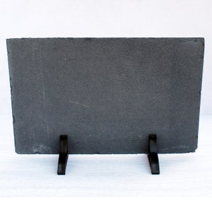 May include: A black slate plaque with a textured surface and two black metal kickstands. The plaque is blank and ready for personalization.