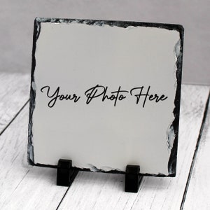 May include: A white slate photo frame with a black slate border and a stand. The frame has a white background with the text "Your Photo Here" written in black.