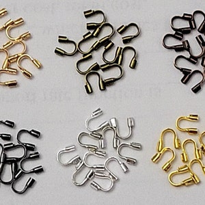 May include: A selection of metal crimp end findings in gold, bronze, black, and silver. These small, U-shaped components are used in jewellery making to secure cords or chains.