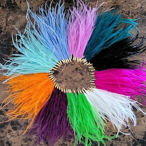 May include: Assortment of 10 feather boas in various colours, including teal, pink, white, orange, purple, green, and black. The feathers are arranged in a circle with gold jump rings connecting them.