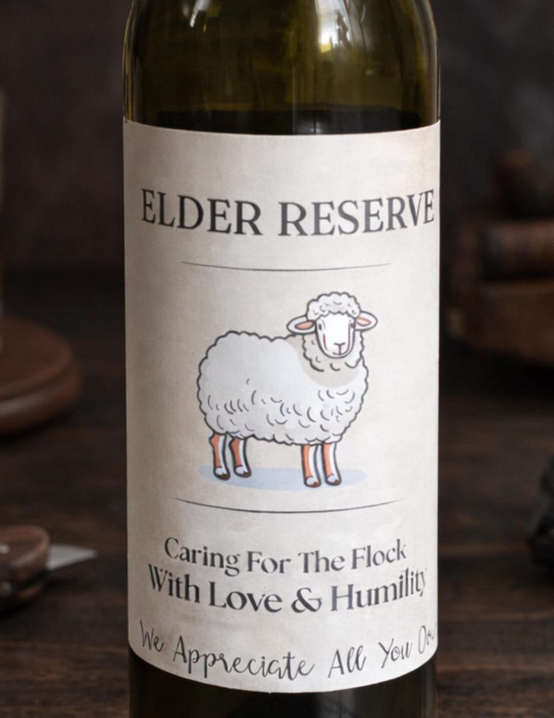 May include: A wine bottle with a label that reads "ELDER RESERVE" above a cartoon sheep illustration. Below the sheep, the label says "Caring For The Flock With Love & Humility We Appreciate All You". The bottle is green.