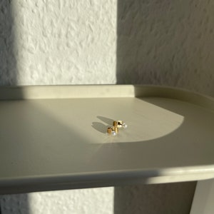 Peut inclure: Une paire de boucles d'oreilles en or avec de petits accents de perles blanches.