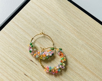 May include: A pair of gold hoop earrings with colourful beads. The beads are arranged in a spiral pattern around the hoop.