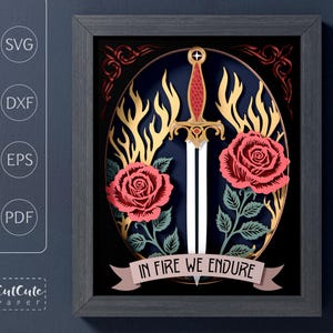 May include: Framed paper art with a sword, roses, and flames. The design features a sword with a red handle, two red roses, and gold flames against a dark blue background. The text "IN FIRE WE ENDURE" is on a banner. The frame is dark grey.