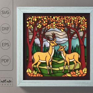 May include: A framed paper art piece featuring two deer in a forest scene. The artwork uses layered paper to create a 3D effect, with autumn-colored trees and a green and yellow landscape. The frame is light blue, and the artwork includes the text "CutCute Paper".