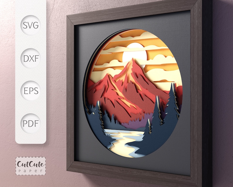 May include: A papercraft mountain scene with a red mountain, blue trees, and a yellow sun in a circular frame. The frame is brown wood with a black mat.