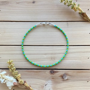 Puede incluir: Un collar de cuentas verde y azul con un cierre plateado.