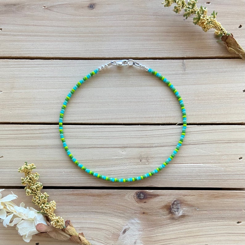 Puede incluir: Un collar de cuentas verde y azul con un cierre plateado.