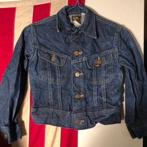 May include: A blue denim jacket with a button closure, two chest pockets, and a label that reads "Lee" on the left chest pocket.