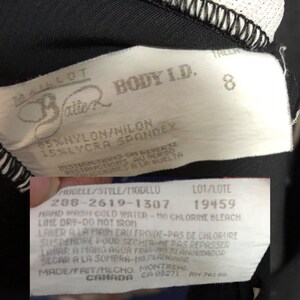 May include: Close-up of a clothing tag with the brand name "Balle" and "BODY I.D." printed on it. The tag also includes the size "8" and fabric composition: 85% nylon/nilon, 15% lycra spandex. Additional text includes care instructions.