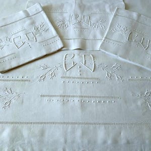 Puede incluir: Juego de ropa de cama de lino blanco con diseños florales bordados e iniciales. El juego incluye una sábana grande y dos fundas de almohada a juego. El bordado es detallado y añade un toque de elegancia a la tela blanca clásica.