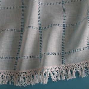 Puede incluir: Tela blanca transparente con un patrón de cuadrícula y un borde de crochet blanco.