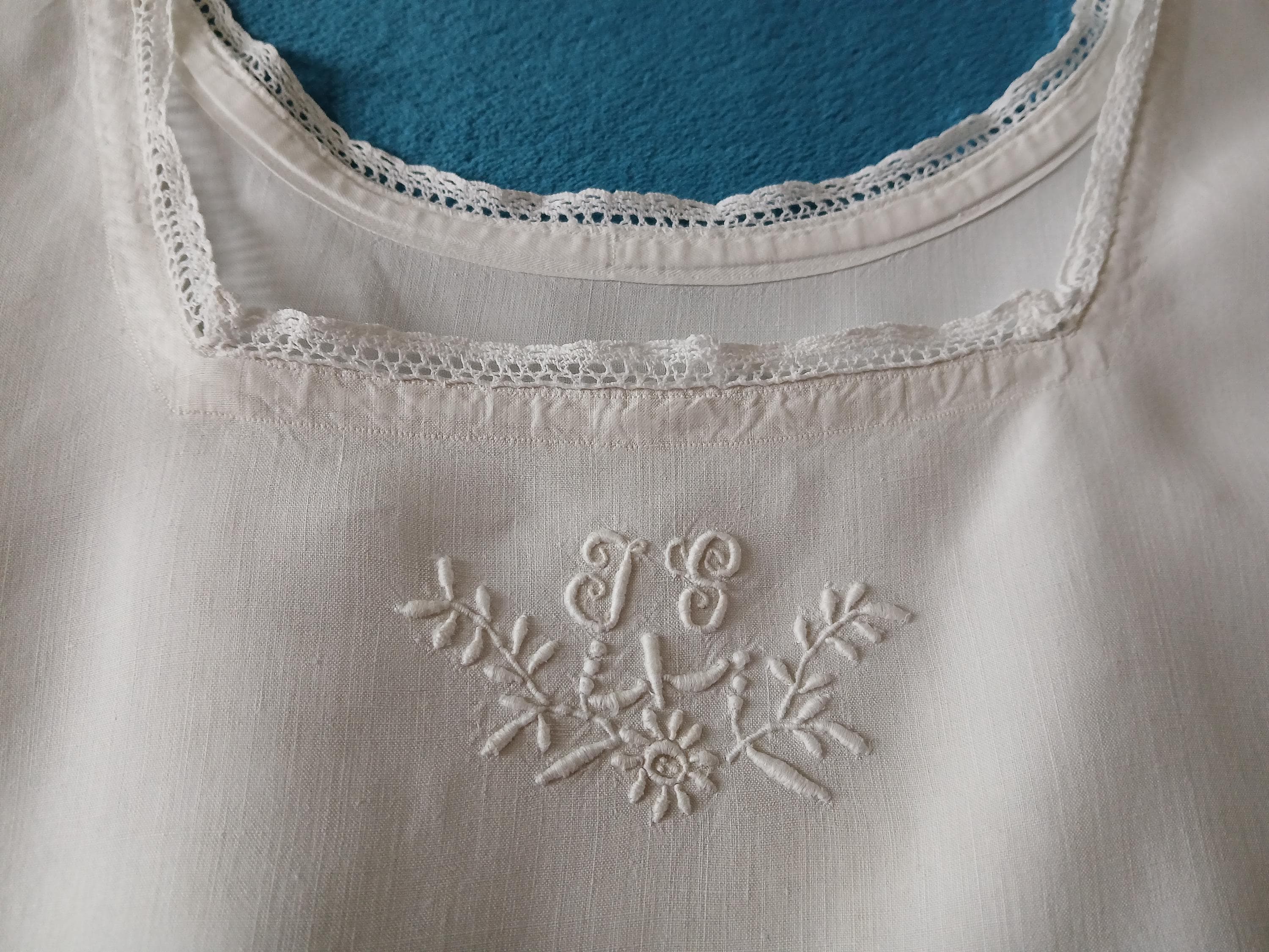 An antique French night dress in smooth pure linen with hand embroidered floral monogram JS and lace edging.  Medium