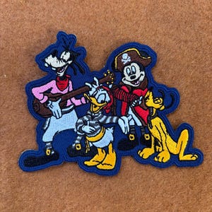 May include: An embroidered patch featuring four Disney characters dressed as pirates.  Goofy is playing a guitar, Donald Duck is holding a sword, Mickey Mouse is wearing a pirate hat and holding a sword, and Pluto is standing next to Mickey Mouse.