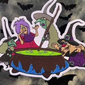 Puede incluir: Parche bordado con cuatro brujas revolviendo un caldero de líquido verde. Las brujas llevan sombreros puntiagudos y ropa verde, morada y roja. El caldero está sobre un lecho de llamas azules.