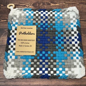 May include: A blue, gray, and white woven potholder with a brown tag that reads "Artisan Loomed Potholders The Red Door Barntique 100% Cotton Made in Tamaha, OK www.reddoorbarntique.com"