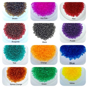 May include: Assortment of small, round, colorful beads in various shades of brown, hot pink, red, burgundy, black, purple, teal, orange, blue, spiced orange, green, and yellow. The beads are displayed in clear glass bowls.