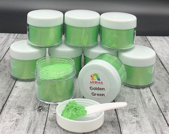 May include: A group of eight small jars of green mica powder, with one jar open and a small scoop of powder next to it. The jars are labeled "Aroma Bead Depot" and "Golden Green".