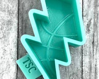 May include: A teal blue silicone mold shaped like a lightning bolt with a raised "TSC" logo on the bottom.