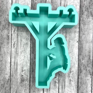 May include: A light green silicone mold of a utility pole with a lineman working on it. The mold is designed for making resin crafts.