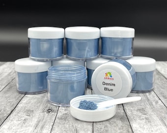 May include: Eight small jars of blue food coloring powder, stacked in a pyramid shape. The jar in the front has a white label that reads "Aroma Food Craft Denim Blue".