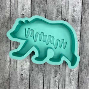 May include: A light green silicone mold shaped like a bear with the word "mama" inscribed inside.