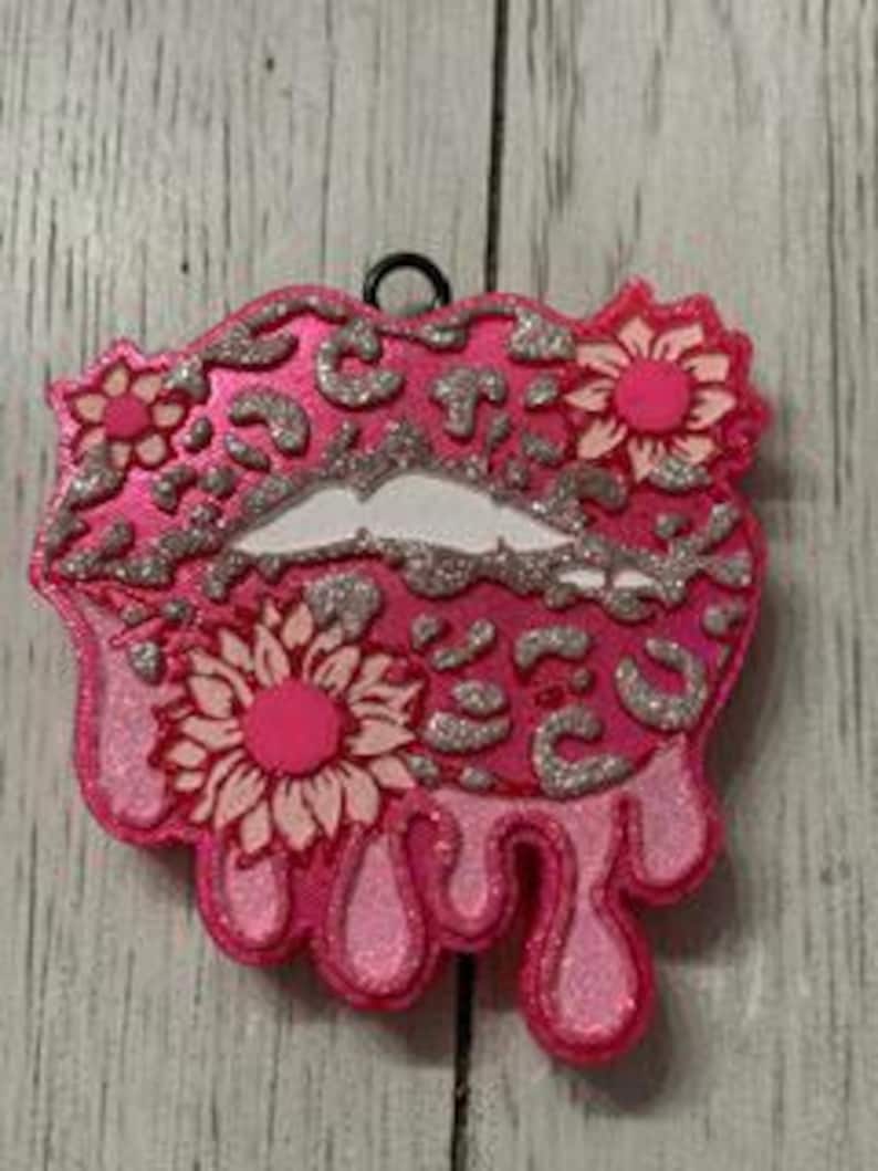 May include: Pink glitter lips with a leopard print design and white flowers. The lips are dripping with pink glitter.