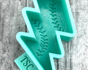 May include: A teal blue silicone mold shaped like a lightning bolt with a baseball stitch design. The mold has the text "TSC" on the bottom.