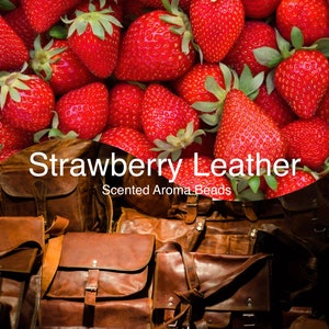 May include: Image features a vibrant display of fresh red strawberries with green leaves, contrasted by a collection of brown leather bags. The text "Strawberry Leather" and "Scented Aroma Beads" is overlaid on the image.