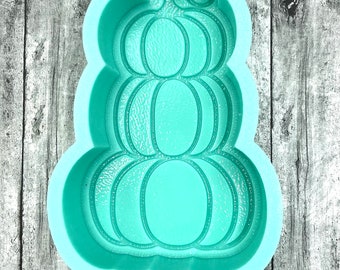 May include: A teal blue silicone mould shaped like a stack of three pumpkins with a swirl design on top. The mould has the letters "ABD" at the bottom.