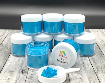 May include: Eight small jars of light turquoise mica powder, with one jar open and a scoop of powder in a small white dish. The jar in the center has a label that reads "Aroma Bead Supply Lt Turquoise".