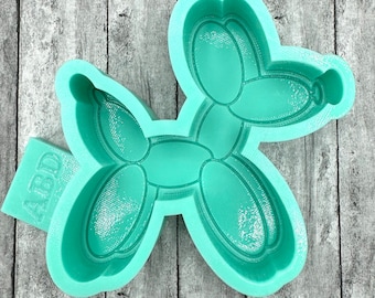 May include: A green silicone mould shaped like a balloon animal dog. The mould has the word "ABD" on the side.
