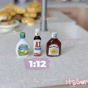 May include: Miniature bottles of Ranch dressing, A1 Original Sauce, and Sweet Baby Ray's Barbecue Sauce are displayed. The bottles are white, red, and brown, with labels. The scale is 1:12.