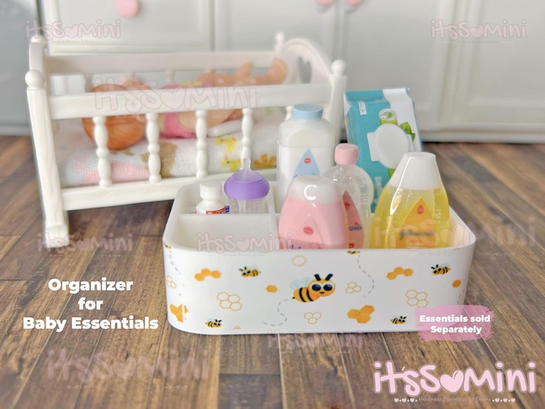 May include: A white organizer with a bee and cloud pattern, holding baby essentials. The organizer contains bottles, a diaper pack, and other baby care items. A white crib is in the background.
