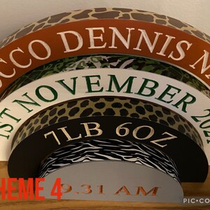 Puede incluir: Un arco de madera de varias capas con un tema de estampado de animales de la selva. El arco est&aacute; decorado con el texto "Rocco Dennis Nash", "1 de noviembre de 2021", "7LB 6OZ" y "THEME 4 9:31 AM".