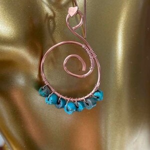 May include: Rose gold wire earrings with a spiral design and turquoise beads.