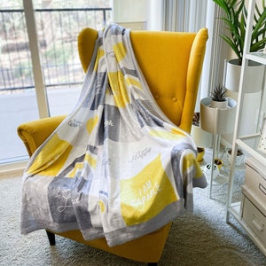 May include: A yellow armchair with a gray and yellow throw blanket. The blanket has the words "I am capable", "I am happy", "I am loved", and "I am enough" printed on it.
