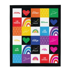May include: A black and white quilt with a colorful patchwork design. Each square features a rainbow, a heart, or a positive affirmation such as "I am strong" or "I am capable".