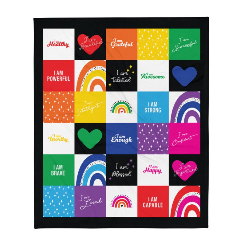 May include: A black and white quilt with a colorful patchwork design. Each square features a rainbow, a heart, or a positive affirmation such as "I am strong" or "I am capable".