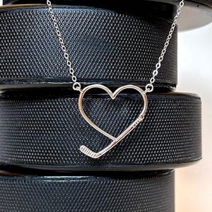 Sterling silver necklace in the shape of a heart with a hockey stick shaped in to the heart design.