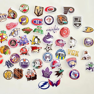 May include: A collection of colorful hockey team logo stickers. The stickers feature various NHL team logos, including the Capitals, Oilers, Blues, and Maple Leafs. The stickers are perfect for decorating laptops, water bottles, or other personal items.
