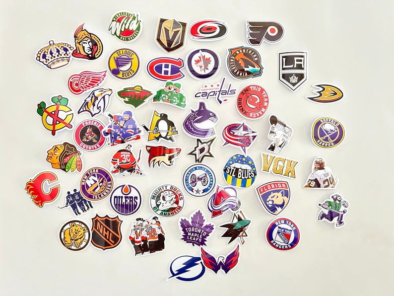 May include: A collection of colorful hockey team logo stickers. The stickers feature various NHL team logos, including the Capitals, Oilers, Blues, and Maple Leafs. The stickers are perfect for decorating laptops, water bottles, or other personal items.