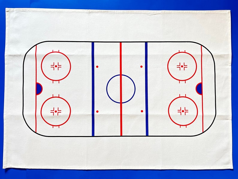 May include: White cotton tea towel with a black and red hockey rink design. The rink has two blue lines, a red center line, and two face-off circles.