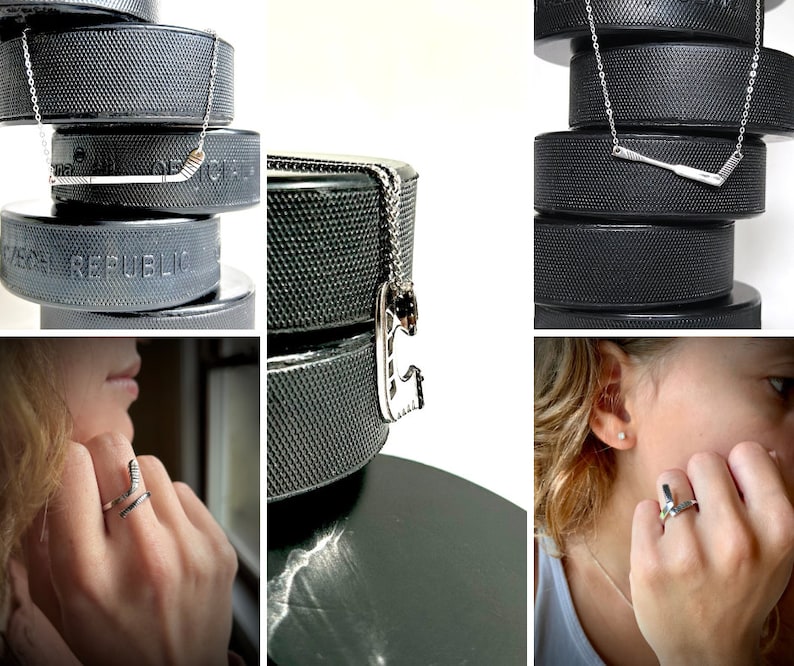 May include: A set of three silver hockey stick necklaces on black hockey pucks. The necklaces feature a silver hockey stick pendant. The pucks are stacked on top of each other.