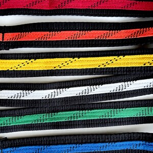 May include: Six martial arts belts with different colored stripes. The belts are black with a red, orange, yellow, white, green, and blue stripe.