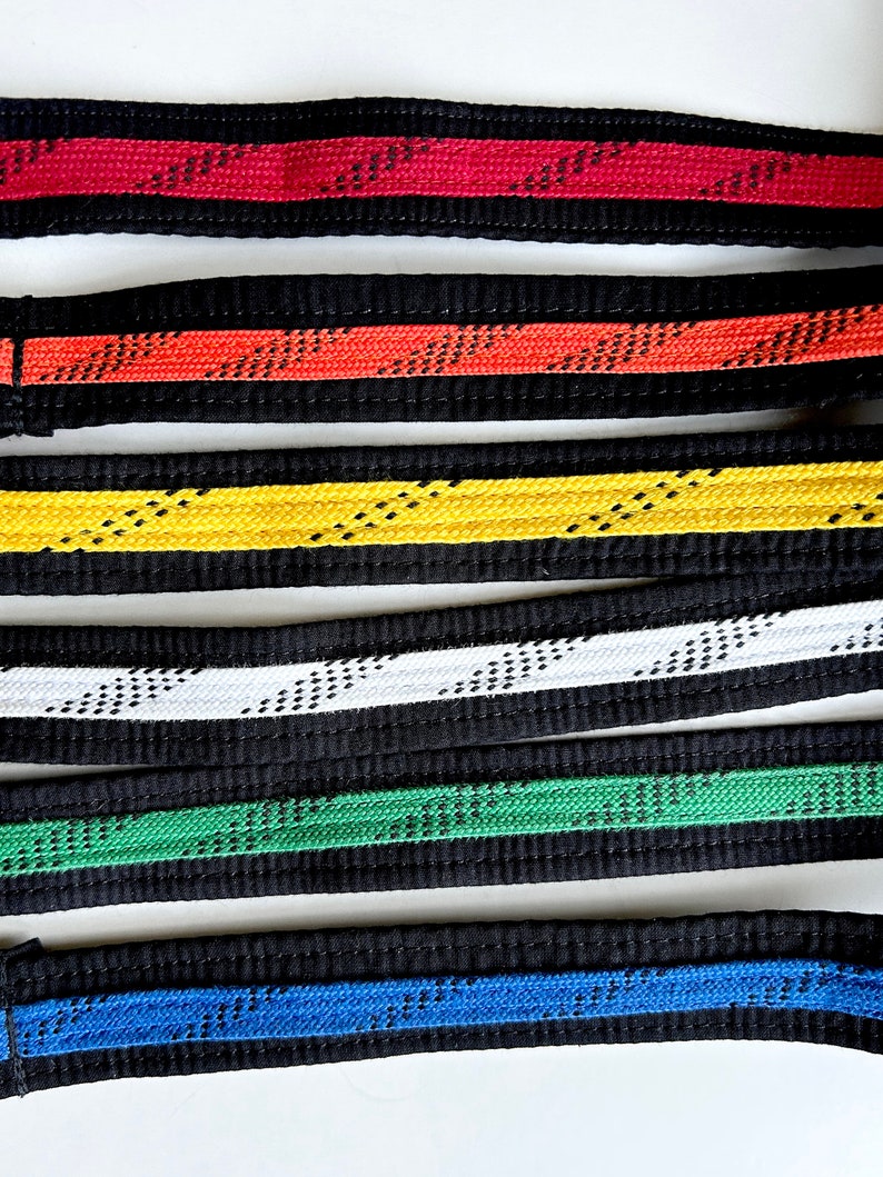 May include: Six martial arts belts with different colored stripes. The belts are black with a red, orange, yellow, white, green, and blue stripe.